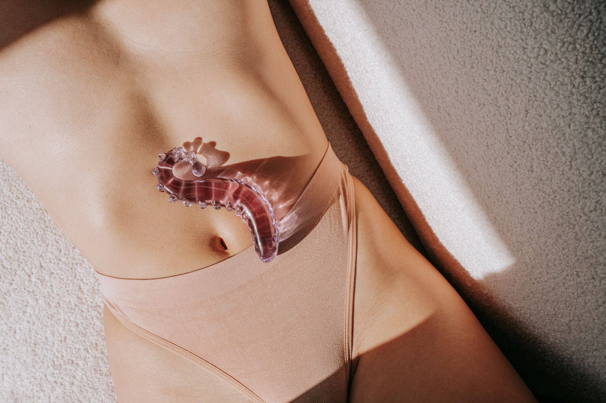 The Sacred Squirter rosa glass-dildo – ergonomisk G-punktstimulering, 13,8 cm, håndlaget i borosilikat-glass med bølget struktur og avrundet tupp.
